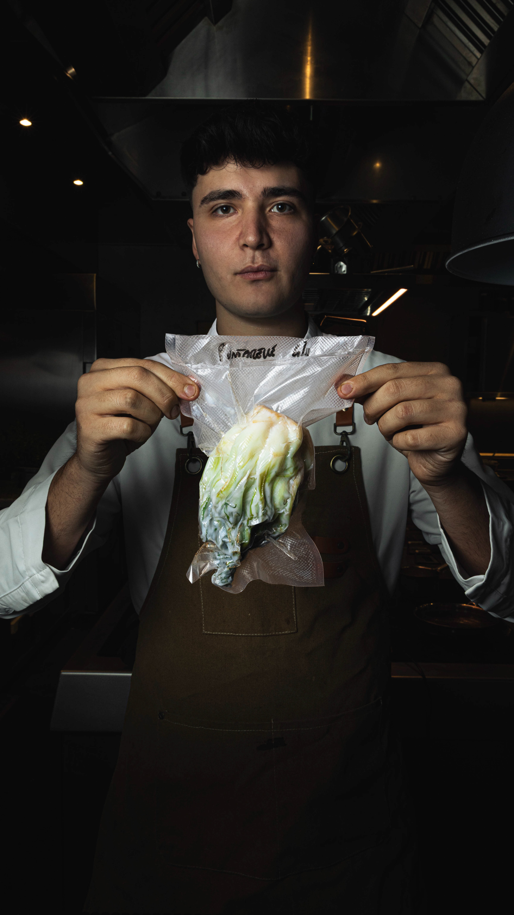 Ritratto di chef in cucina mentre mostra un cespo di verdura sottovuoto — Materiaprima, Pontinia