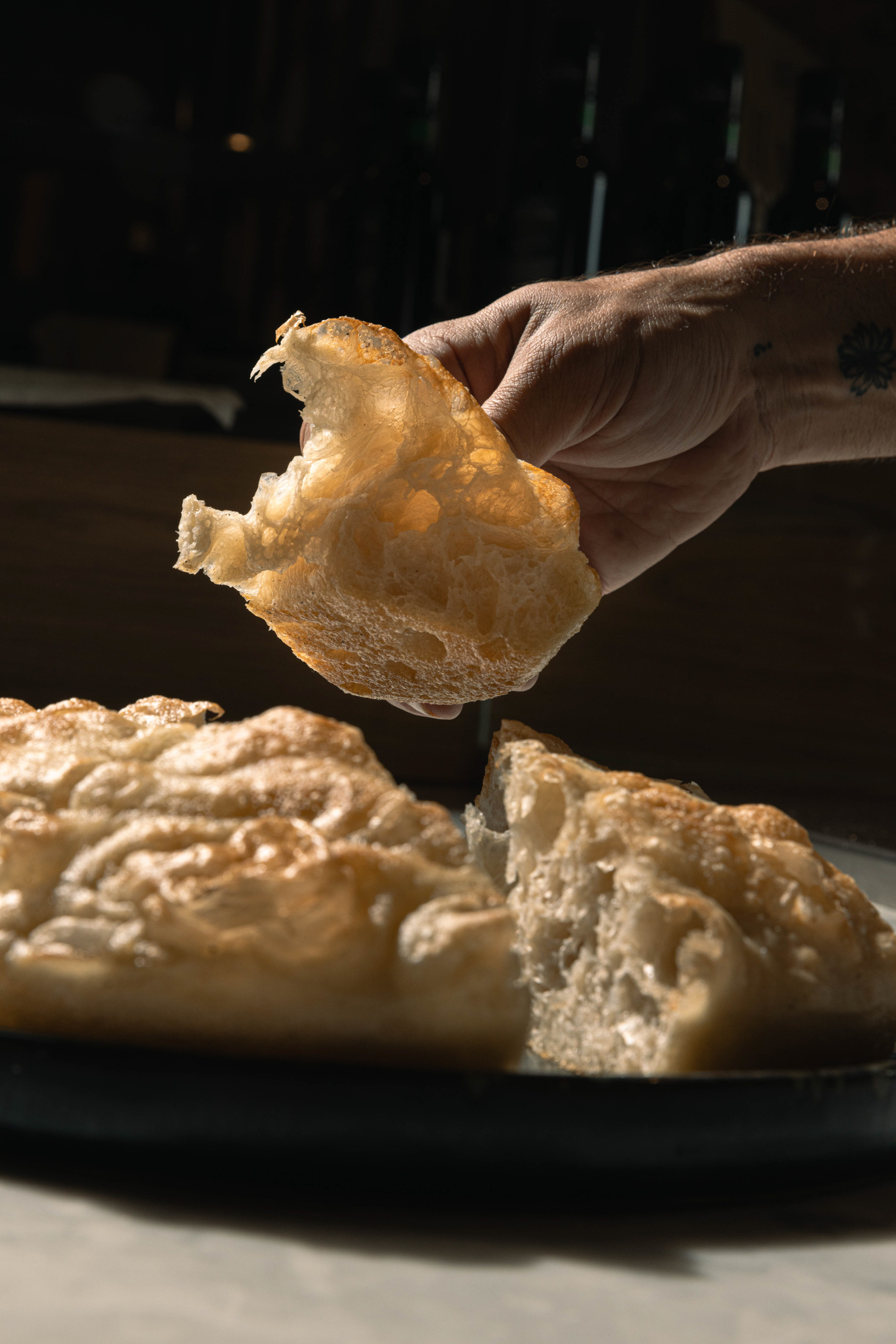 Trancio di pizza in teglia ad alta idratazione sollevato a mano, alveolatura in controluce — La Storta, Latina